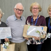 Four people with certificates and gifts