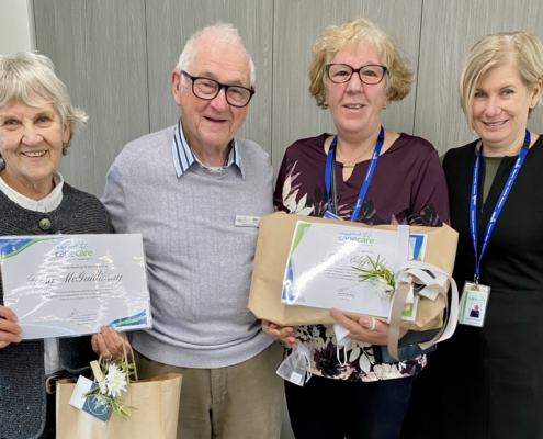 Four people with certificates and gifts
