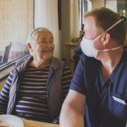 Capecare Busselton female resident Beth Clarke and carer Travis Dean sitting and smiling at each other.