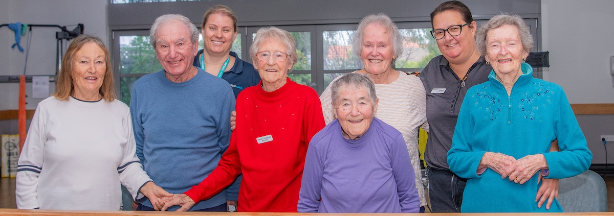 Happy Capecare clients and Allied Health staff pose for a photo in the gym