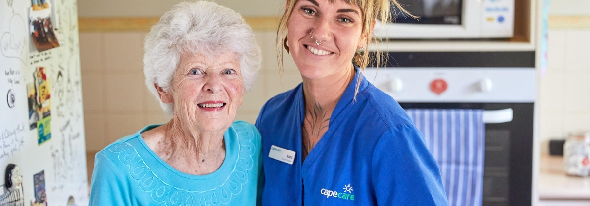 Smiling older woman with her care worker in the kitchen