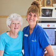 Smiling older woman with her care worker in the kitchen