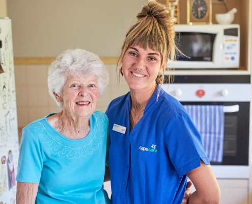 Smiling older woman with her care worker in the kitchen