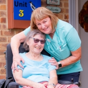 Lady in a wheelchair being hugged by a friendly nurse