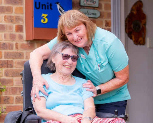 Lady in a wheelchair being hugged by a friendly nurse