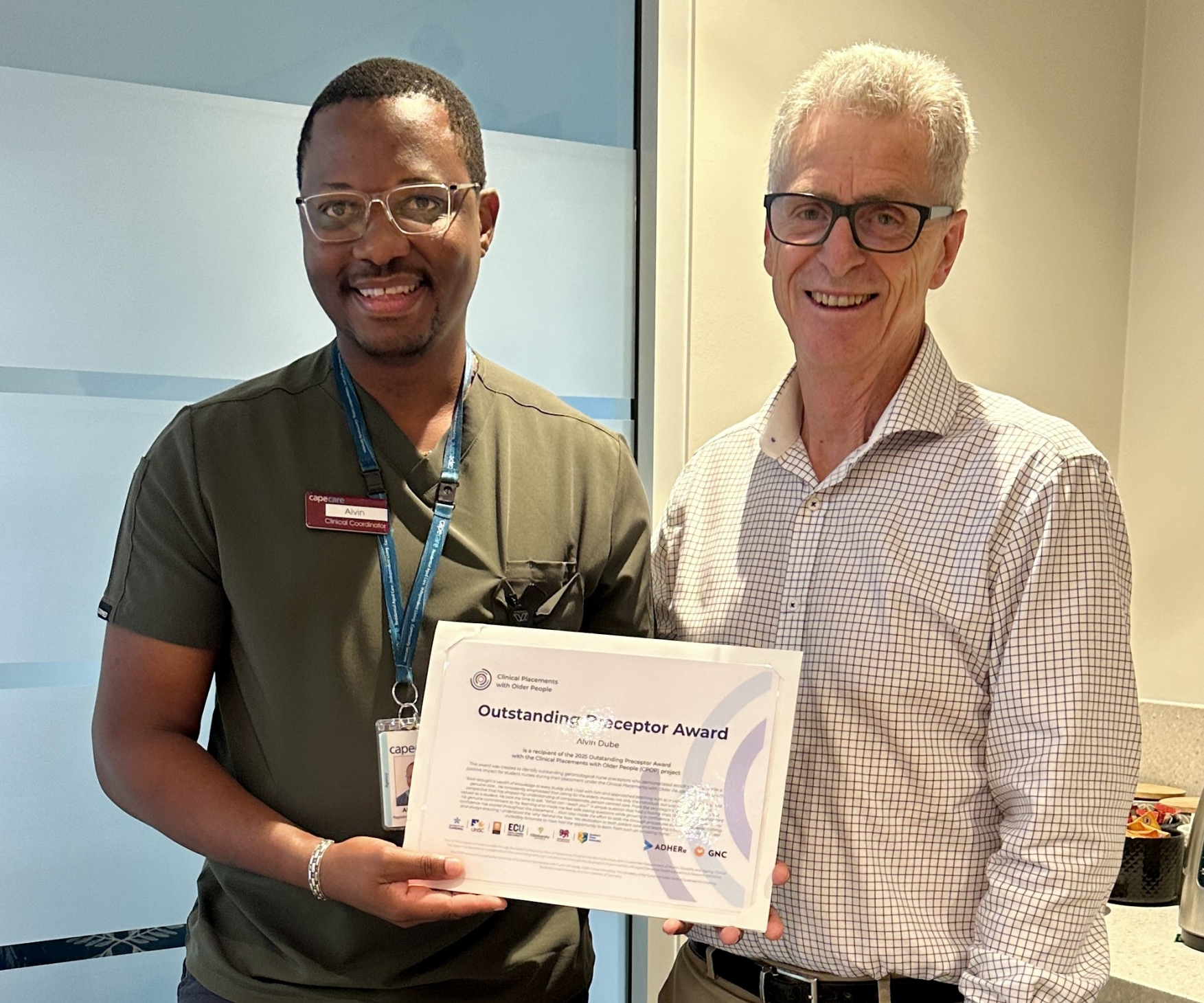 Two men smiling with a certificate.