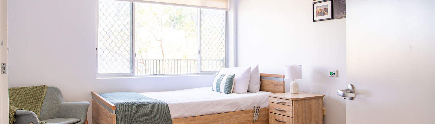 Bright and light respite bedroom with bed and side table and a large window