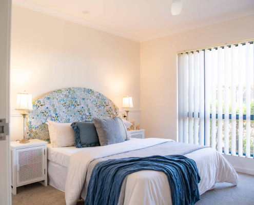 Pretty blue and cream bedroom with fabric bedhead and soft furnishings