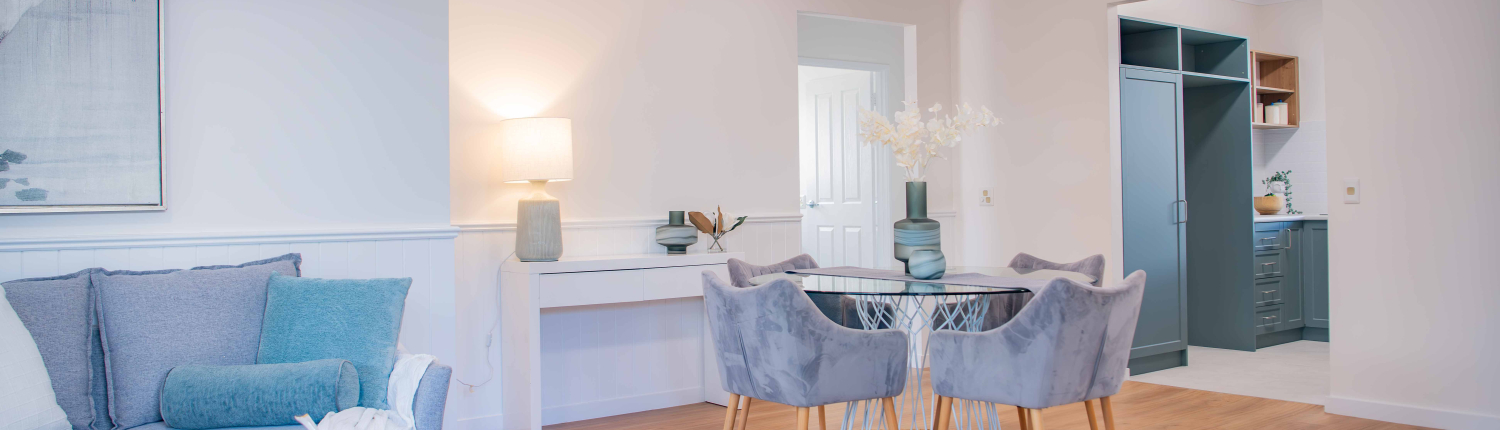 modern dining table with plush grey chairs, timber round table and white walls