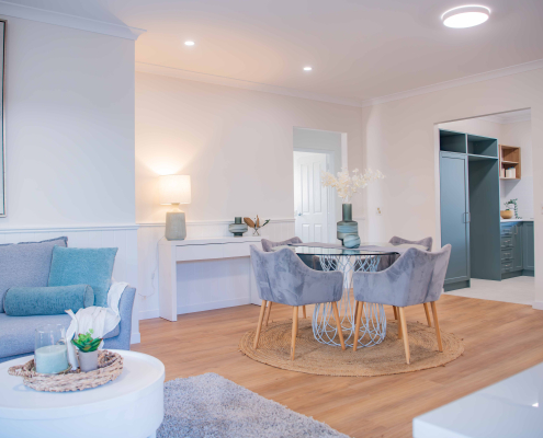 modern dining table with plush grey chairs, timber round table and white walls