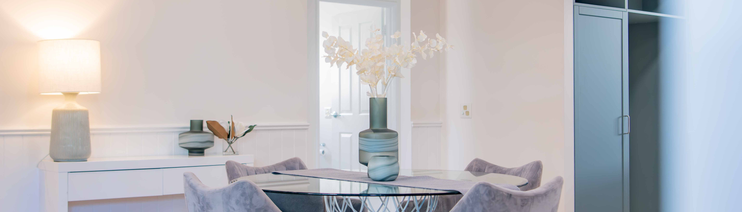 modern dining table with plush grey chairs, timber round table and white walls
