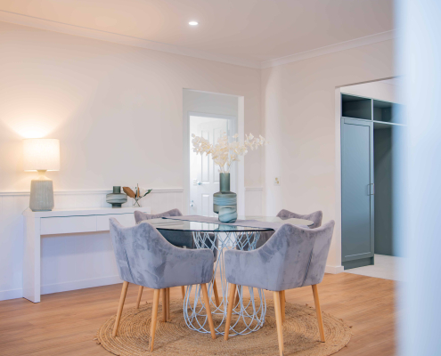 modern dining table with plush grey chairs, timber round table and white walls