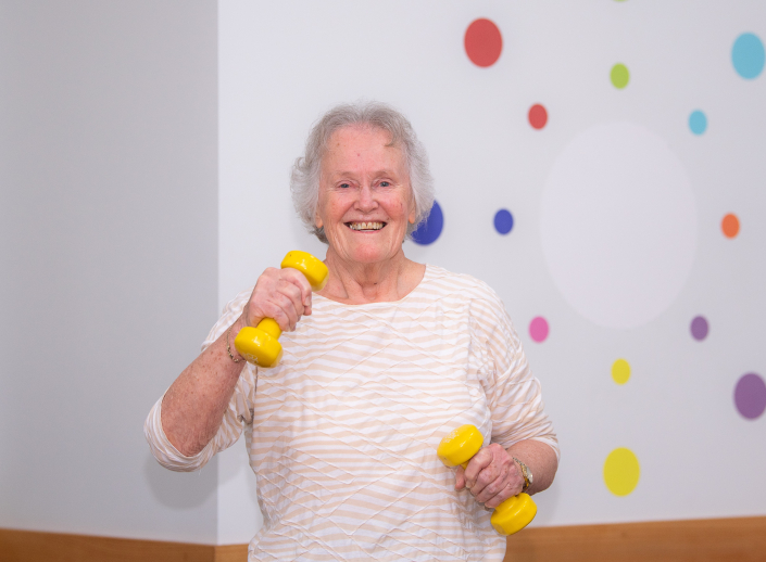 Smiling older lady using small handweights