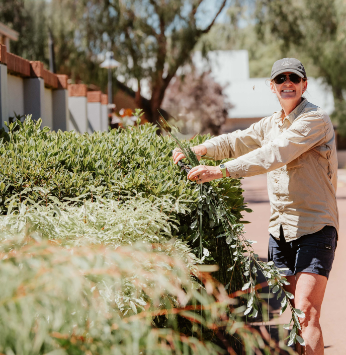 Happy female gardener trimming a hedge