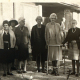 7 elderly women and one man posing for a photograph outside a building. The photograph is sepia and was taken in 1969
